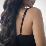 Woman wearing a black strappy top with a blurred background