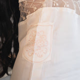 Woman wearing a white lace lingerie set in a softly lit room.